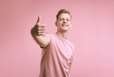 Photo of Happy man showing thumbs up on pink background, space for text. Like gesture