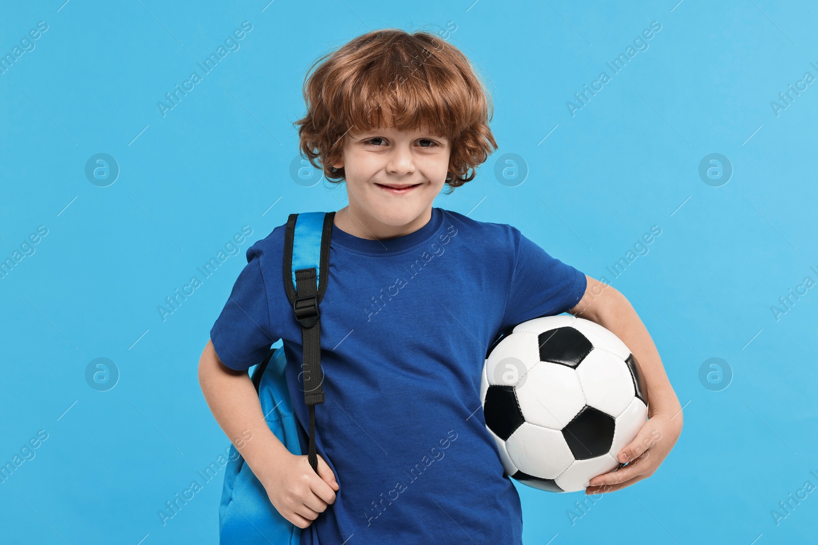 Photo of Little boy with soccer ball and backpack on light blue background