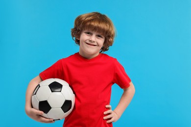 Photo of Little boy with soccer ball on light blue background