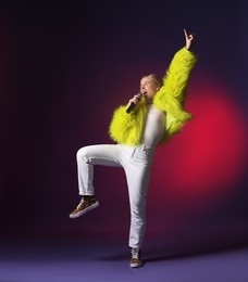 Photo of Talented singer in faux fur performing on dark background with pink light