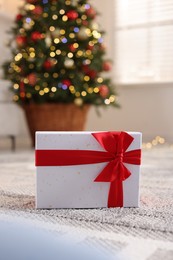 Photo of Christmas gift box on floor indoors, closeup