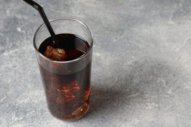 Photo of Refreshing cola with ice cubes and drinking straw in glass on light textured table, closeup. Space for text