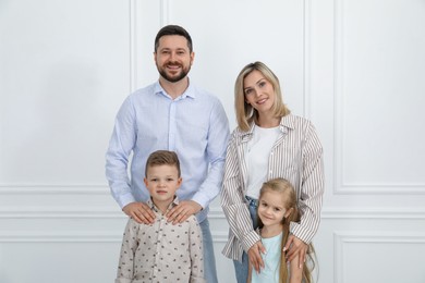 Photo of Happy parents and their children near white wall indoors