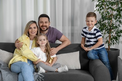 Happy parents and their children on sofa at home