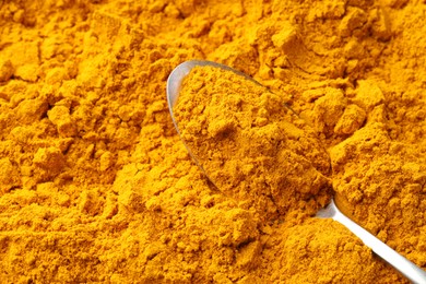 Photo of Turmeric powder in spoon on spice, top view