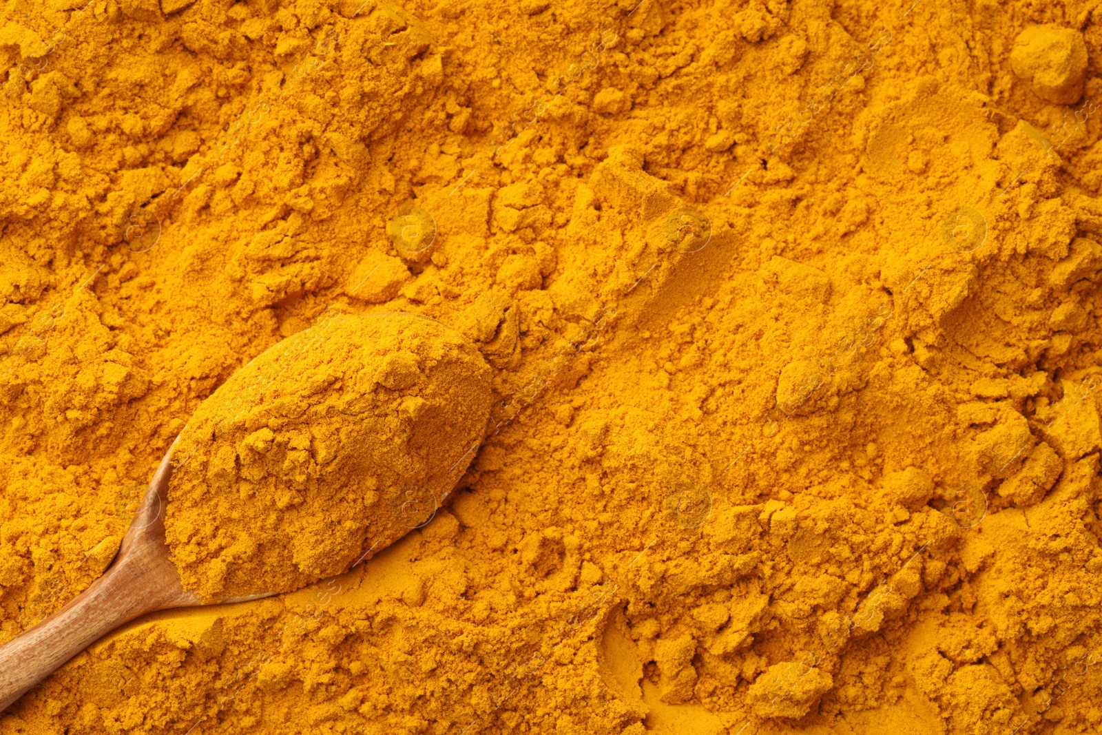 Photo of Turmeric powder in spoon on spice, closeup. Space for text