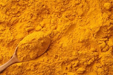 Photo of Turmeric powder in spoon on spice, closeup. Space for text