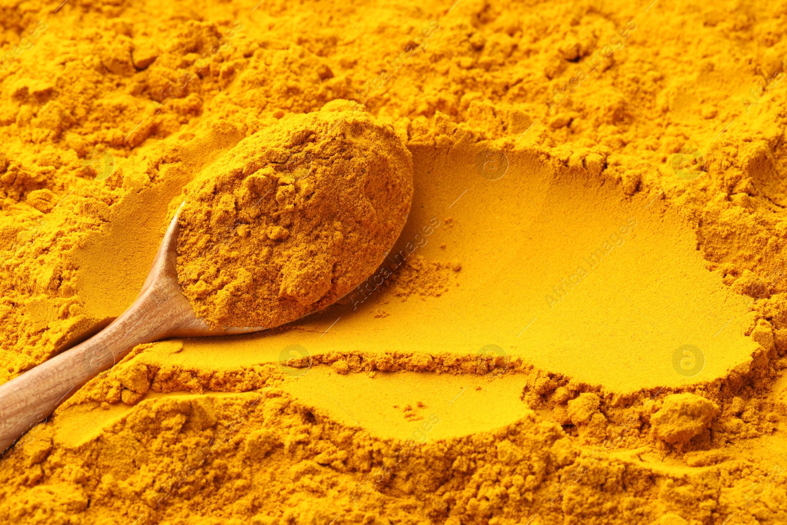 Photo of Turmeric powder in spoon on spice, closeup. Space for text