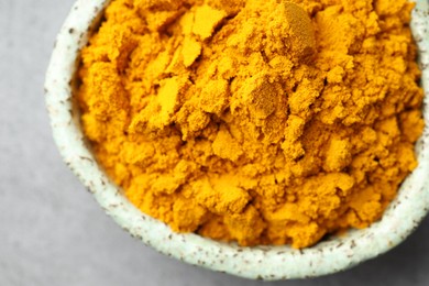 Photo of Turmeric powder in bowl on grey table, top view