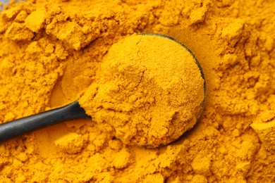 Photo of Spoon on aromatic turmeric powder, top view