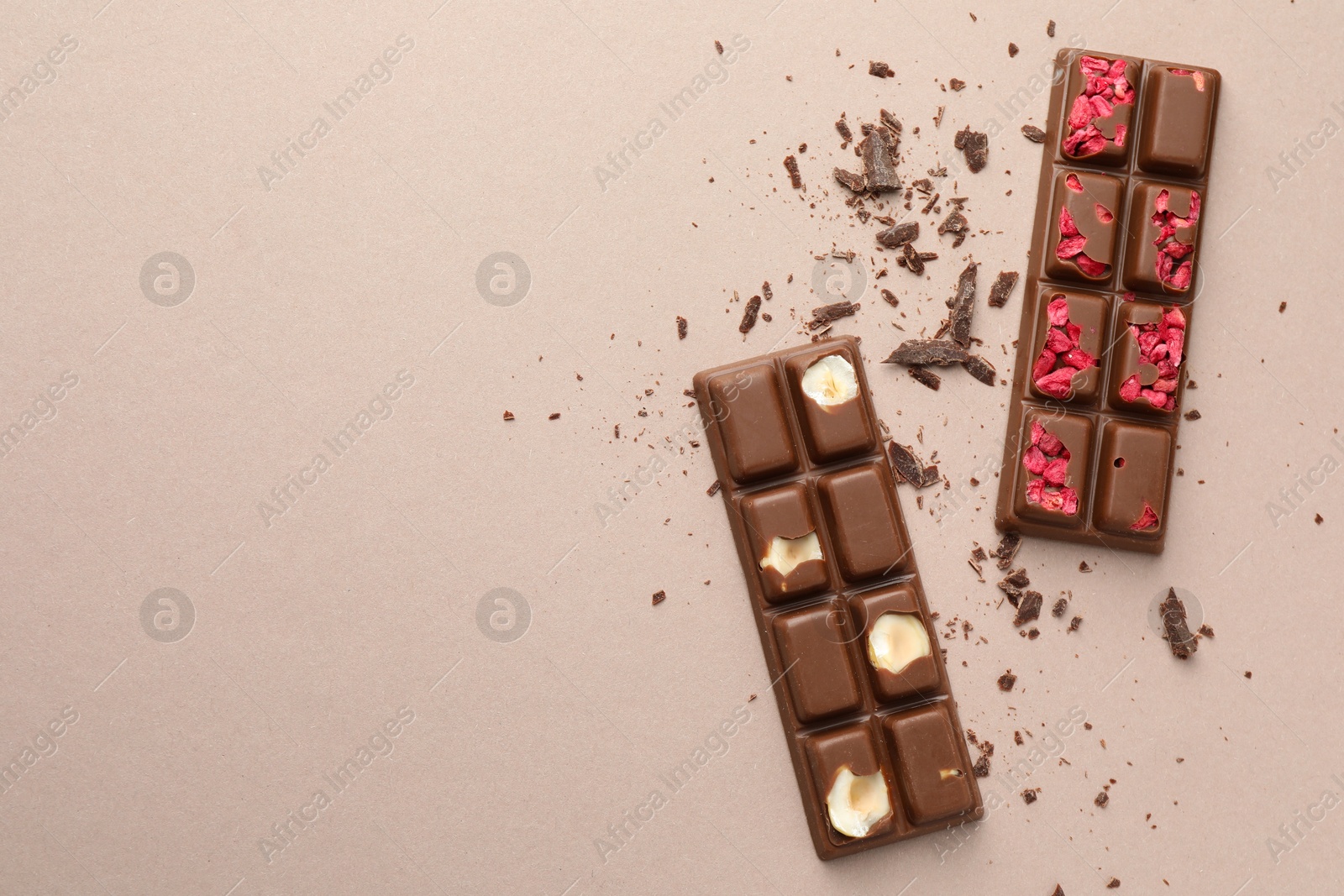 Photo of Tasty chocolate bars and crumbs on beige background, flat lay. Space for text