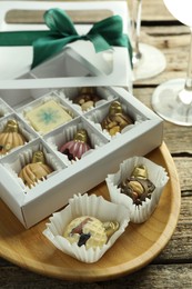 Photo of Box with tasty sweets in shape of baubles on wooden background, closeup