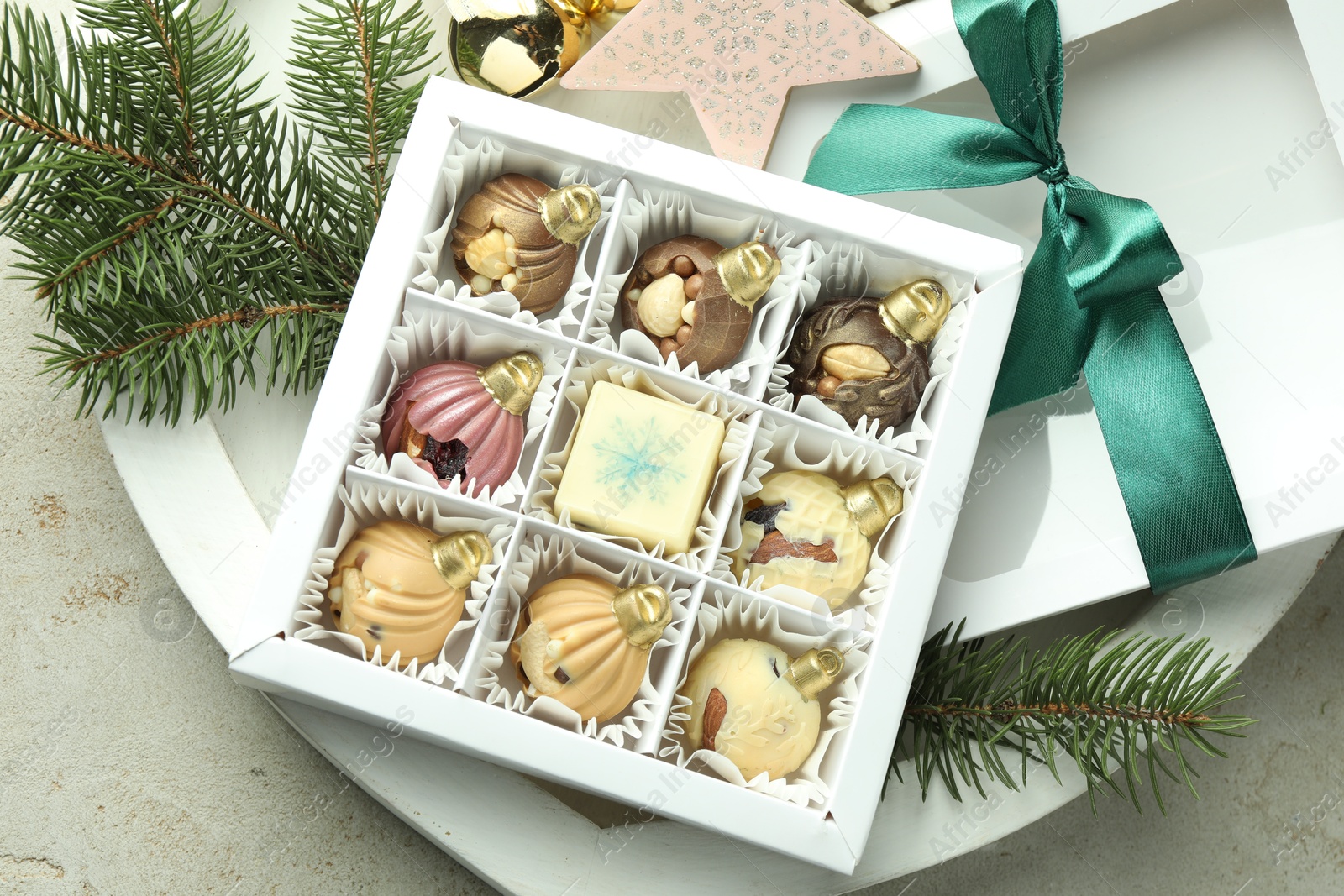 Photo of Box with tasty sweets in shape of baubles and Christmas decor on light background, closeup