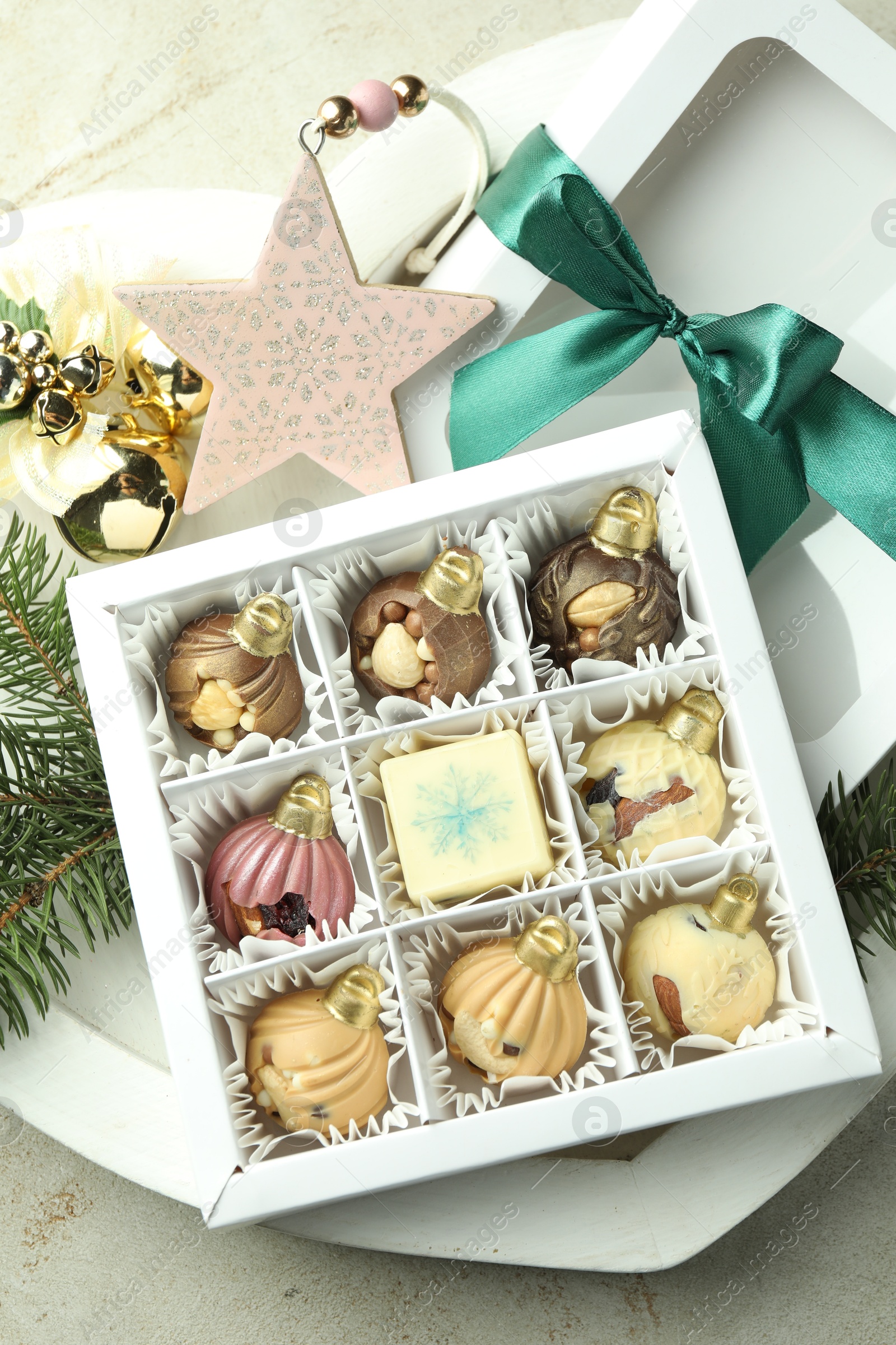 Photo of Box with tasty sweets in shape of baubles and Christmas decor on light background, closeup