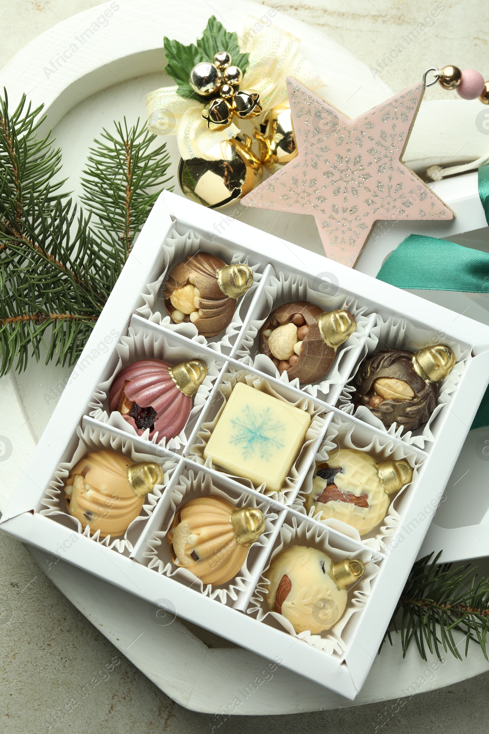 Photo of Box with tasty sweets in shape of baubles and Christmas decor on light background, closeup