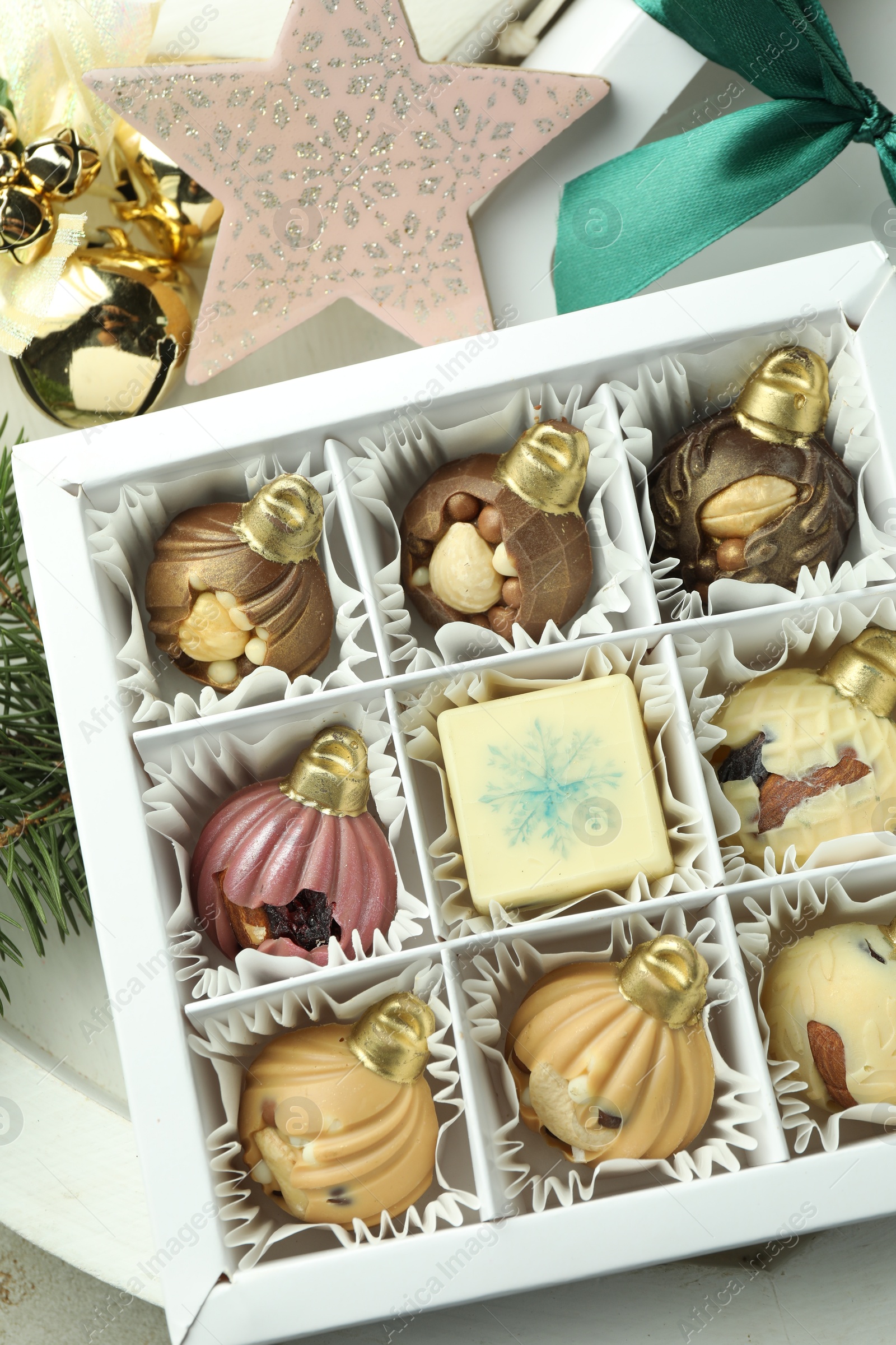 Photo of Box with tasty sweets in shape of baubles and Christmas decor on light background, closeup