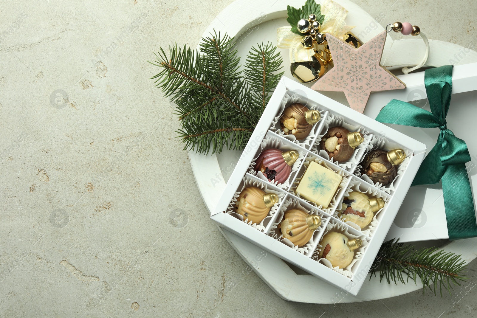 Photo of Box with tasty sweets in shape of baubles and Christmas decor on light background, top view. Space for text