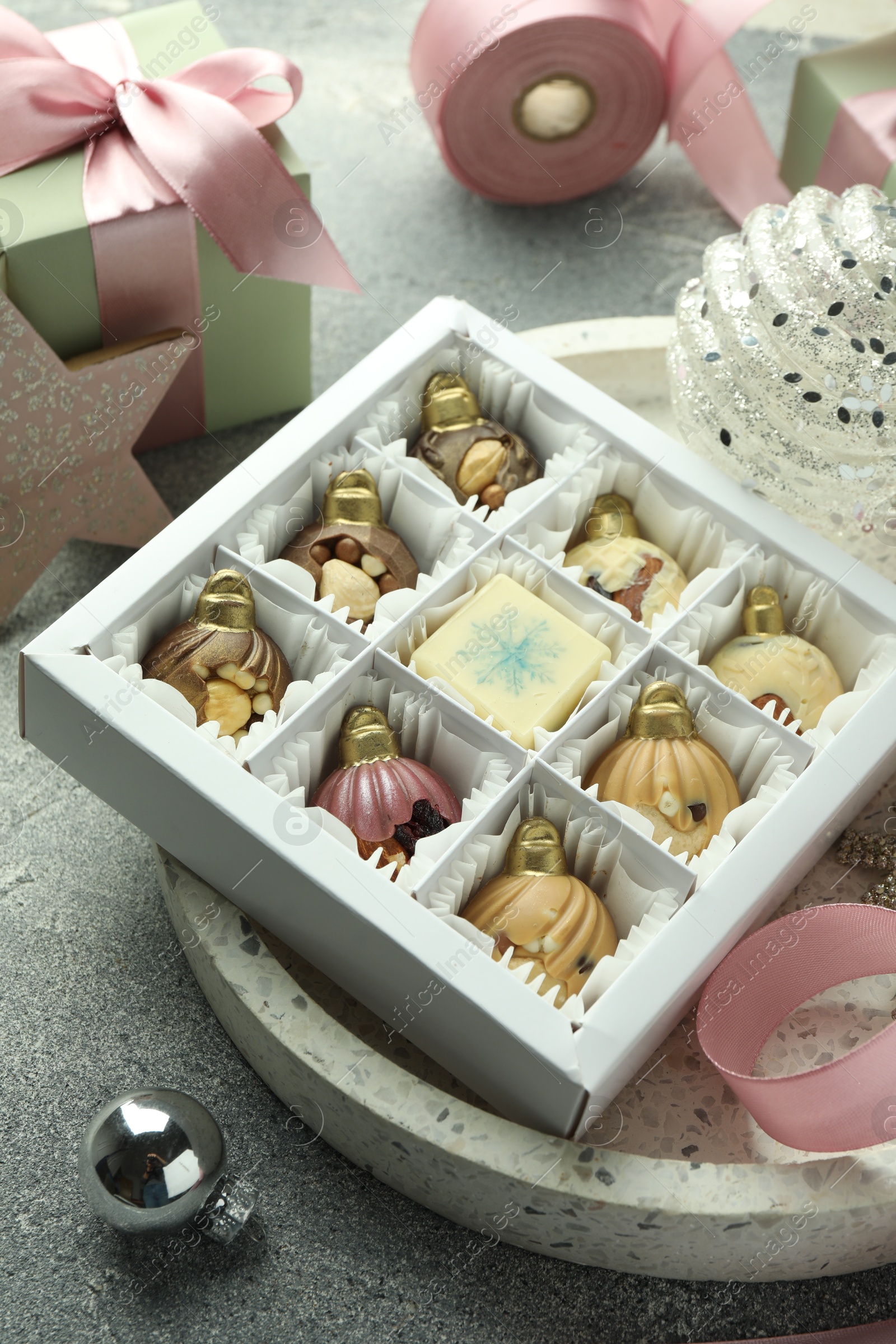 Photo of Box with tasty sweets in shape of baubles and Christmas decor on grey background, closeup