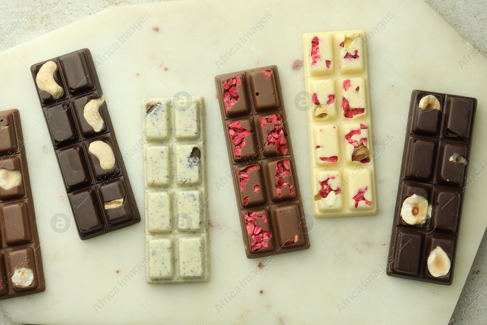 Photo of Delicious chocolate bars with different flavors on light table, top view