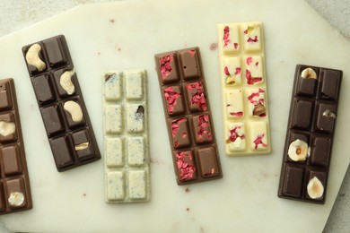 Photo of Delicious chocolate bars with different flavors on light table, top view