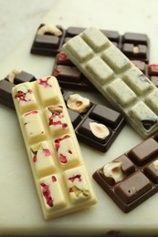 Photo of Delicious chocolate bars with different flavors on light table, closeup