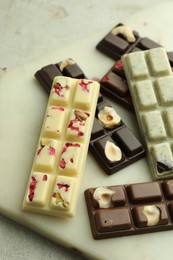 Photo of Delicious chocolate bars with different flavors on light table, closeup