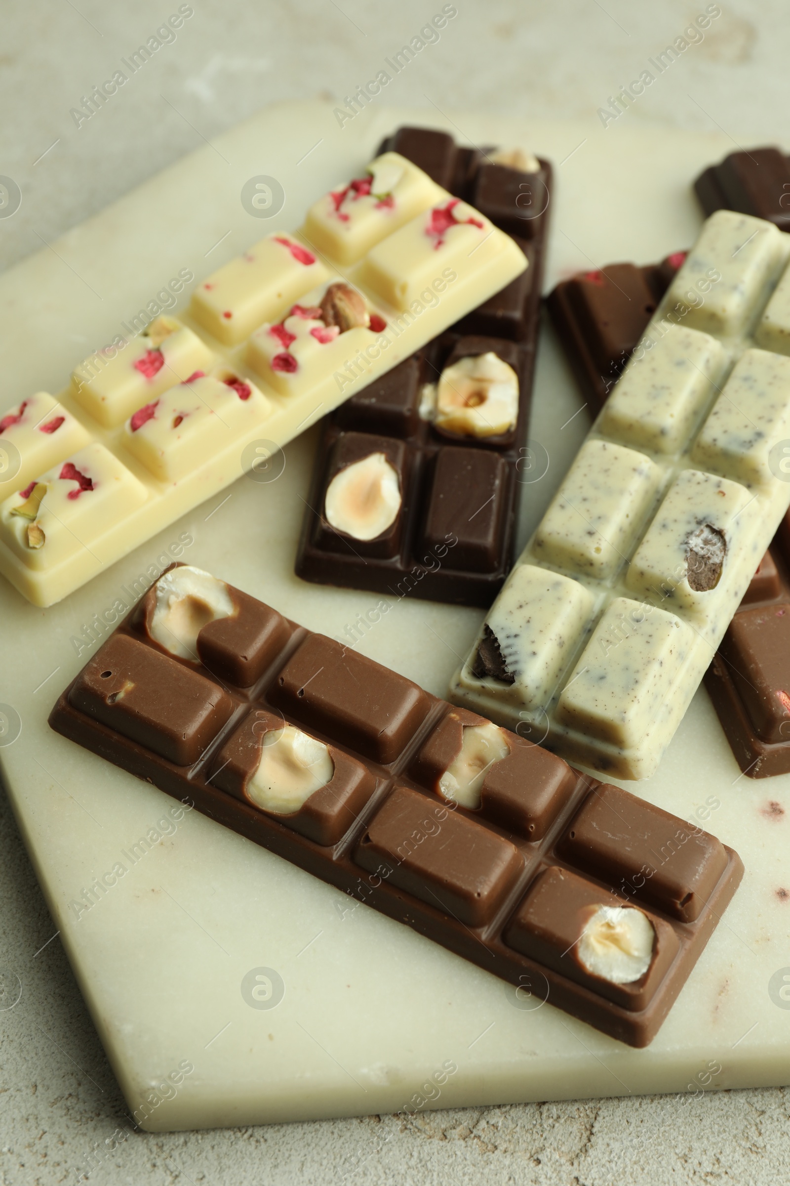 Photo of Delicious chocolate bars with different flavors on light table, closeup