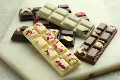 Photo of Delicious chocolate bars with different flavors on light table, closeup