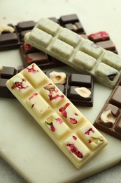 Photo of Delicious chocolate bars with different flavors on light table, closeup