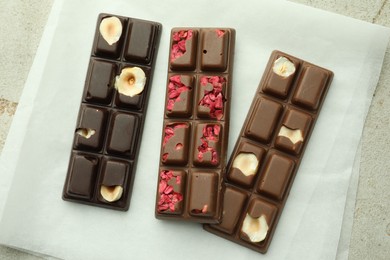 Photo of Delicious chocolate bars with different flavors on light table, flat lay