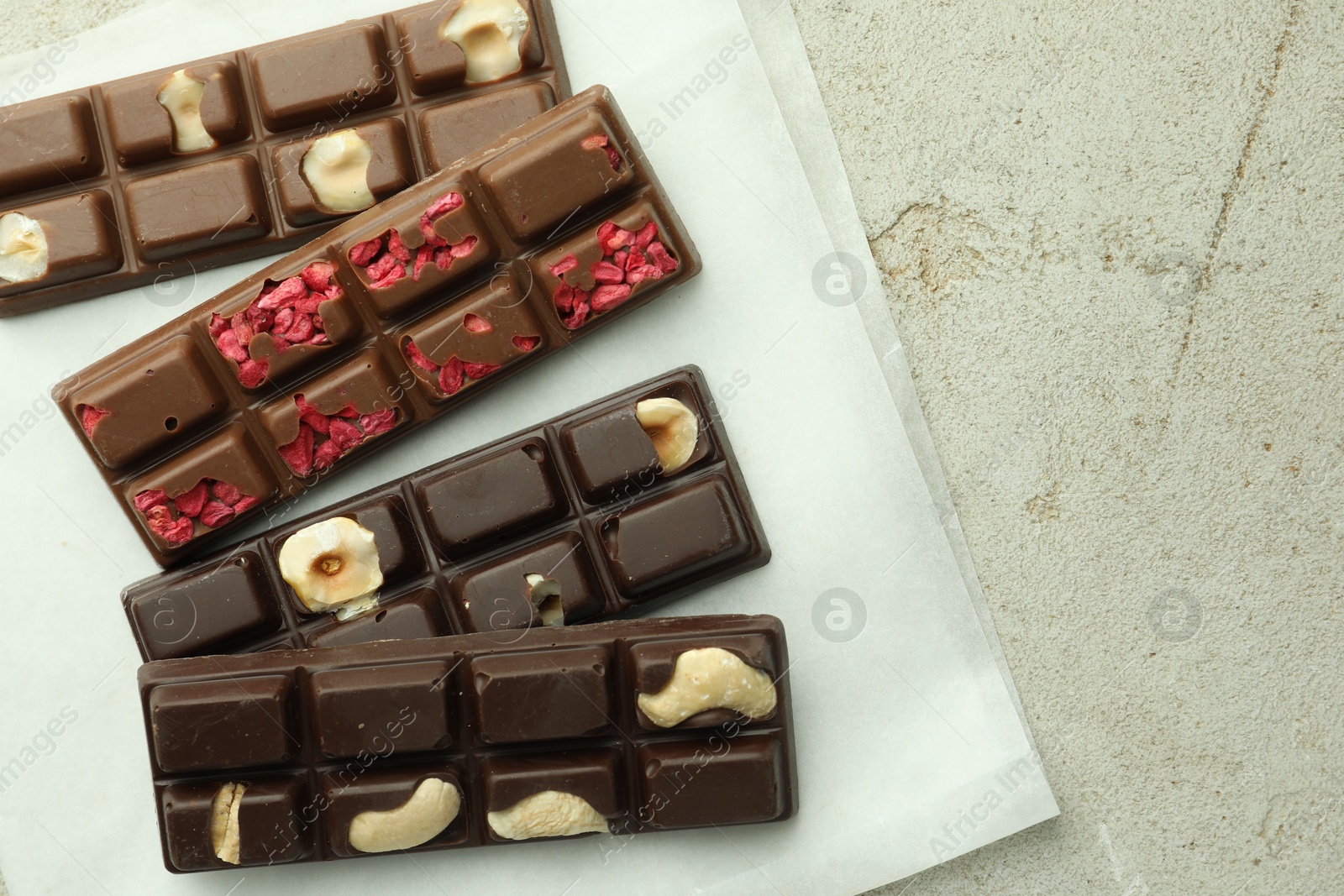 Photo of Delicious chocolate bars with different flavors on light table, flat lay. Space for text