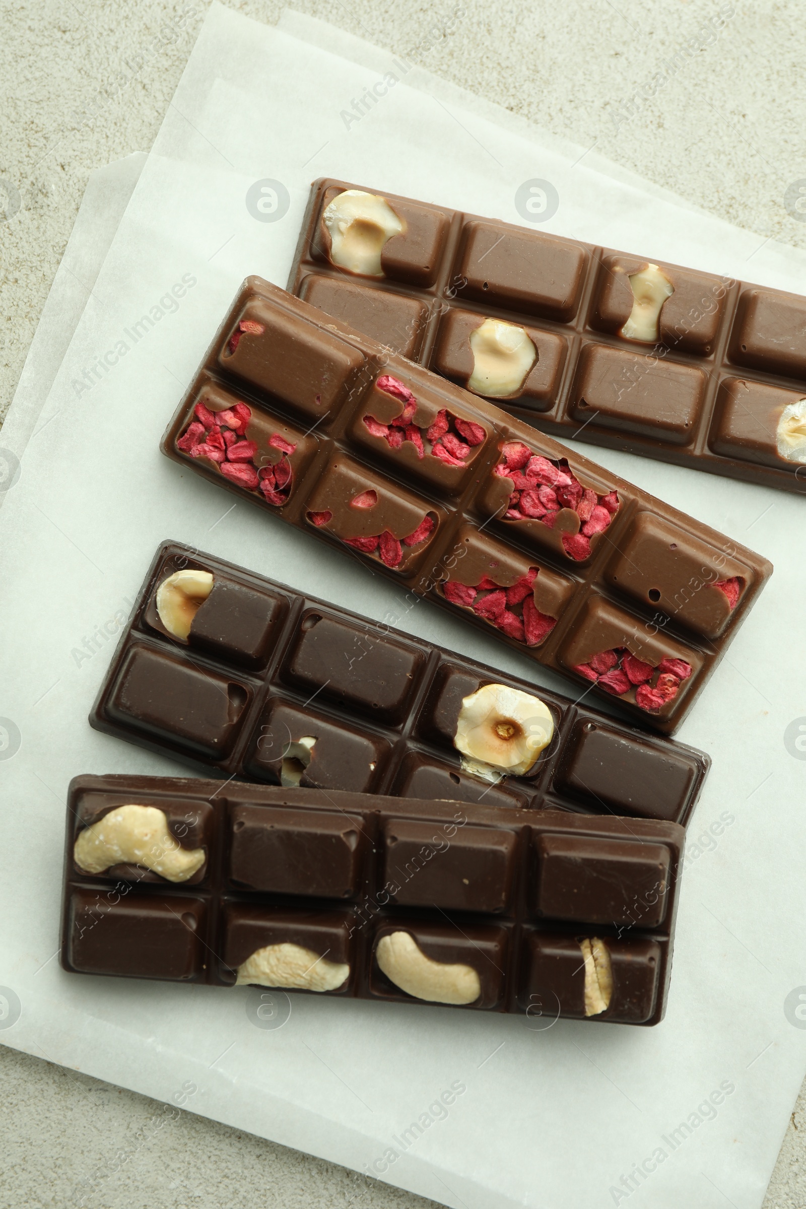 Photo of Delicious chocolate bars with different flavors on light table, flat lay