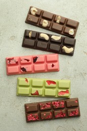 Photo of Delicious chocolate bars with different flavors on light table, flat lay