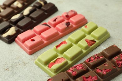 Photo of Delicious chocolate bars with different flavors on light table, closeup