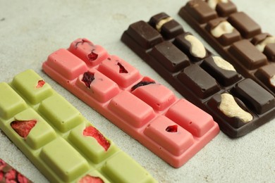 Photo of Delicious chocolate bars with different flavors on light table, closeup