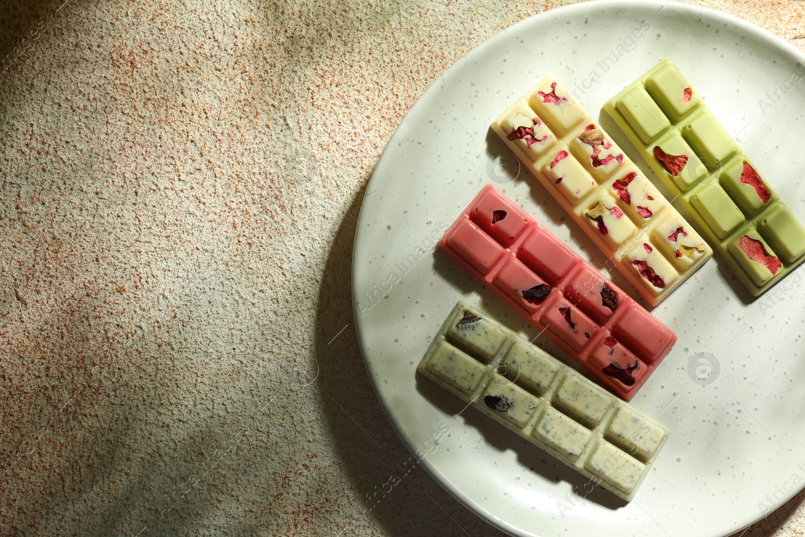 Photo of Delicious chocolate bars with different flavors on light textured table, top view. Space for text