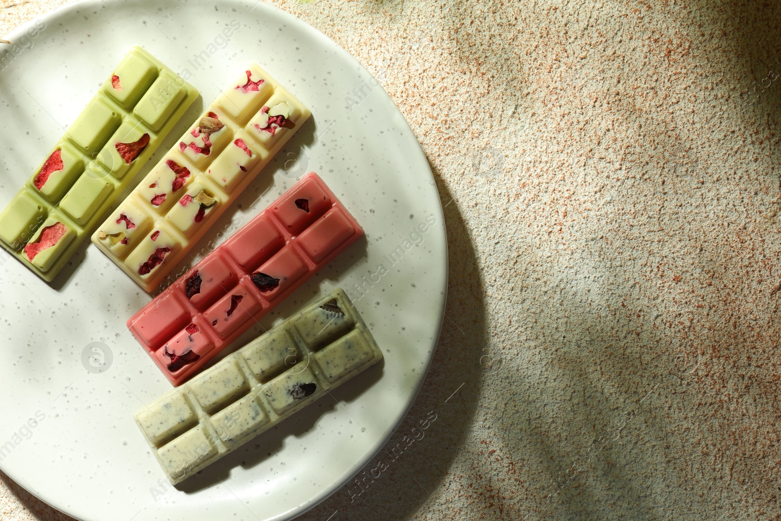 Photo of Delicious chocolate bars with different flavors on light textured table, top view. Space for text