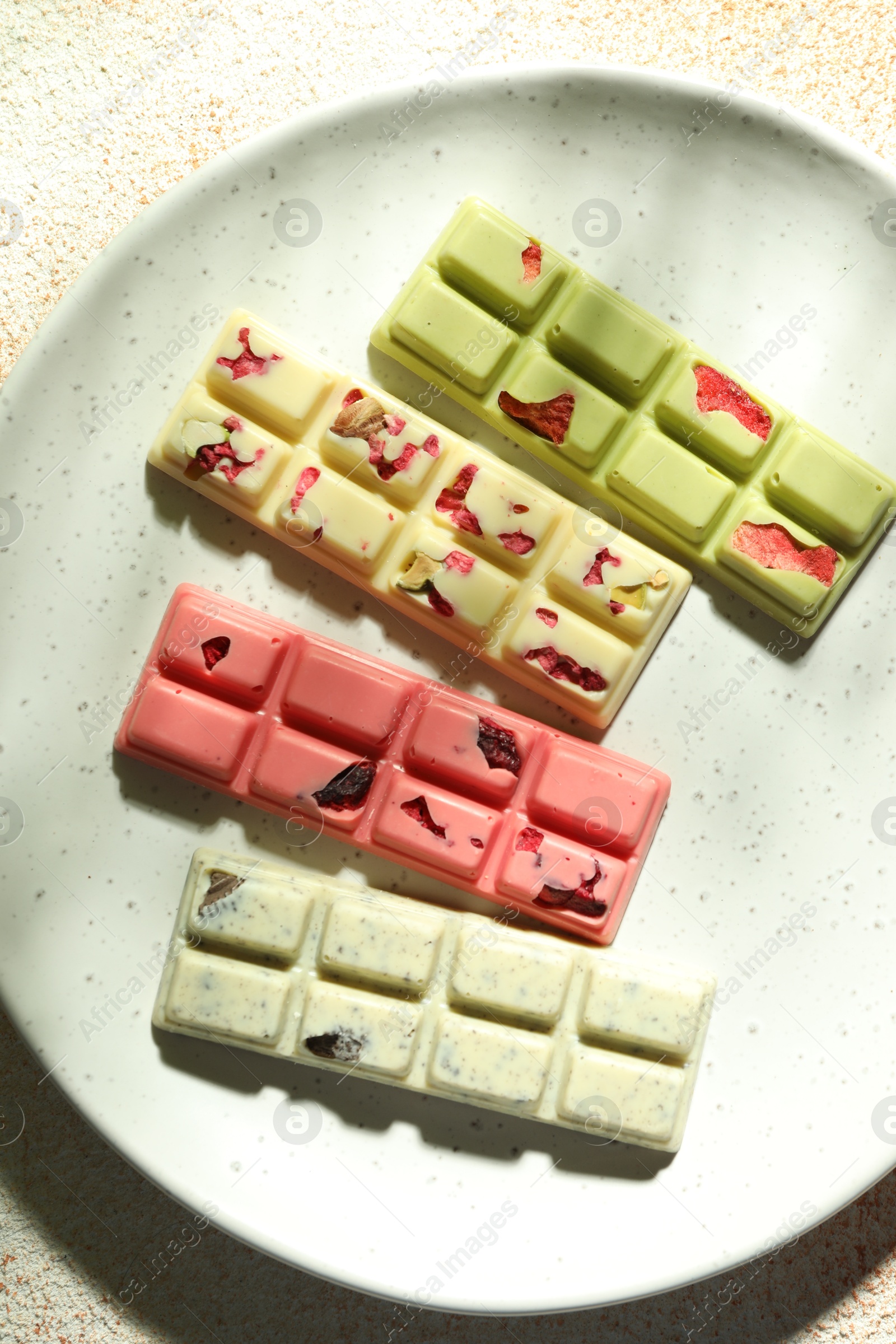 Photo of Delicious chocolate bars with different flavors on light table, top view