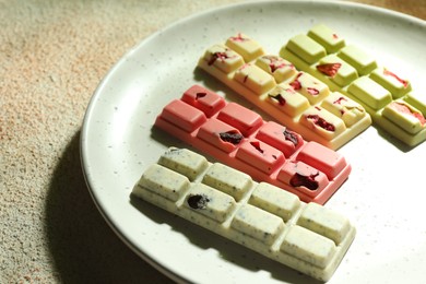 Photo of Delicious chocolate bars with different flavors on light textured table, closeup