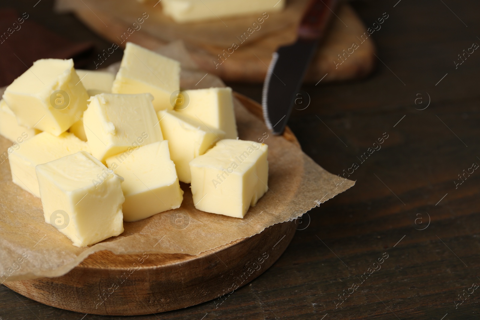 Photo of Pieces of fresh butter on wooden table, closeup. Space for text