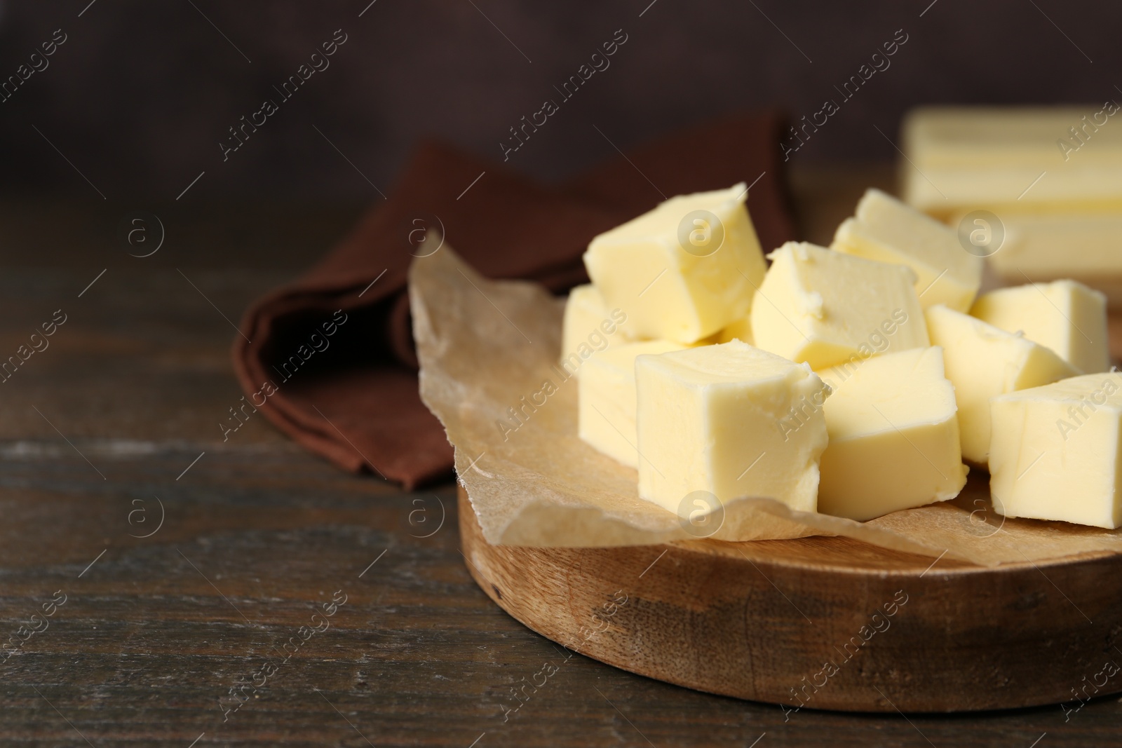 Photo of Pieces of fresh butter on wooden table, closeup. Space for text