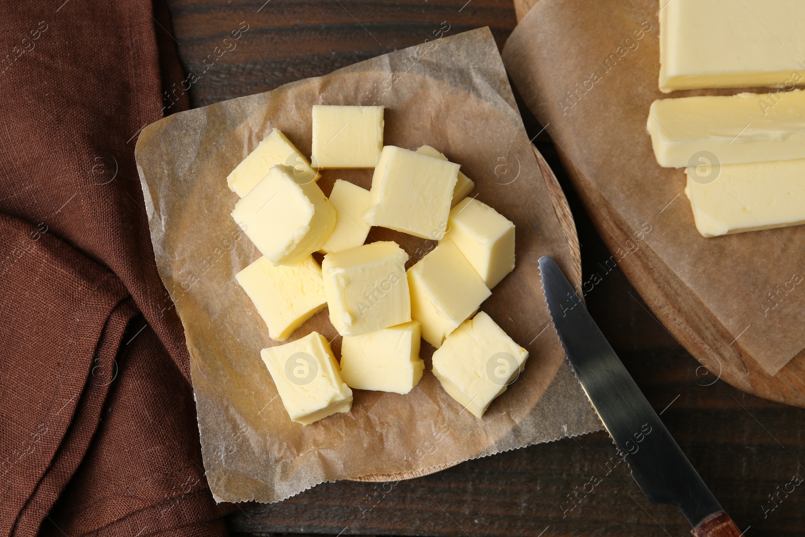 Photo of Pieces of fresh butter and knife on wooden table, flat lay