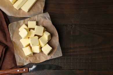 Photo of Pieces of fresh butter and knife on wooden table, flat lay. Space for text