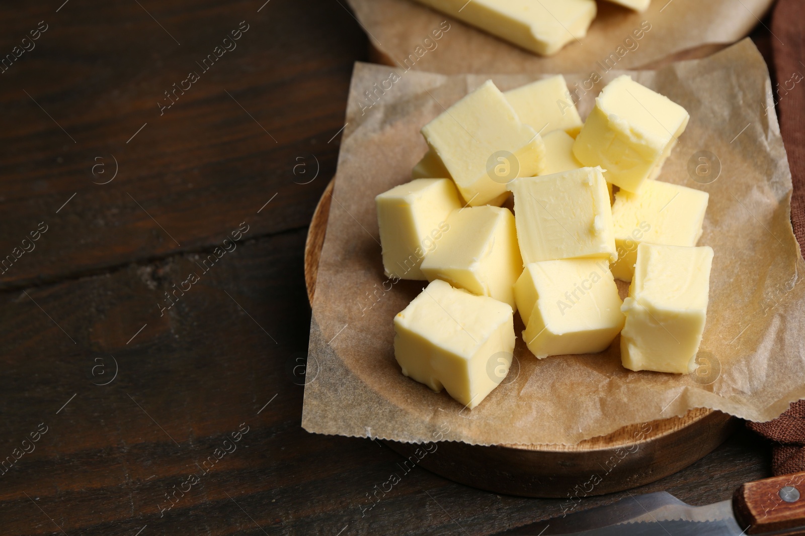 Photo of Pieces of fresh butter on wooden table, closeup. Space for text