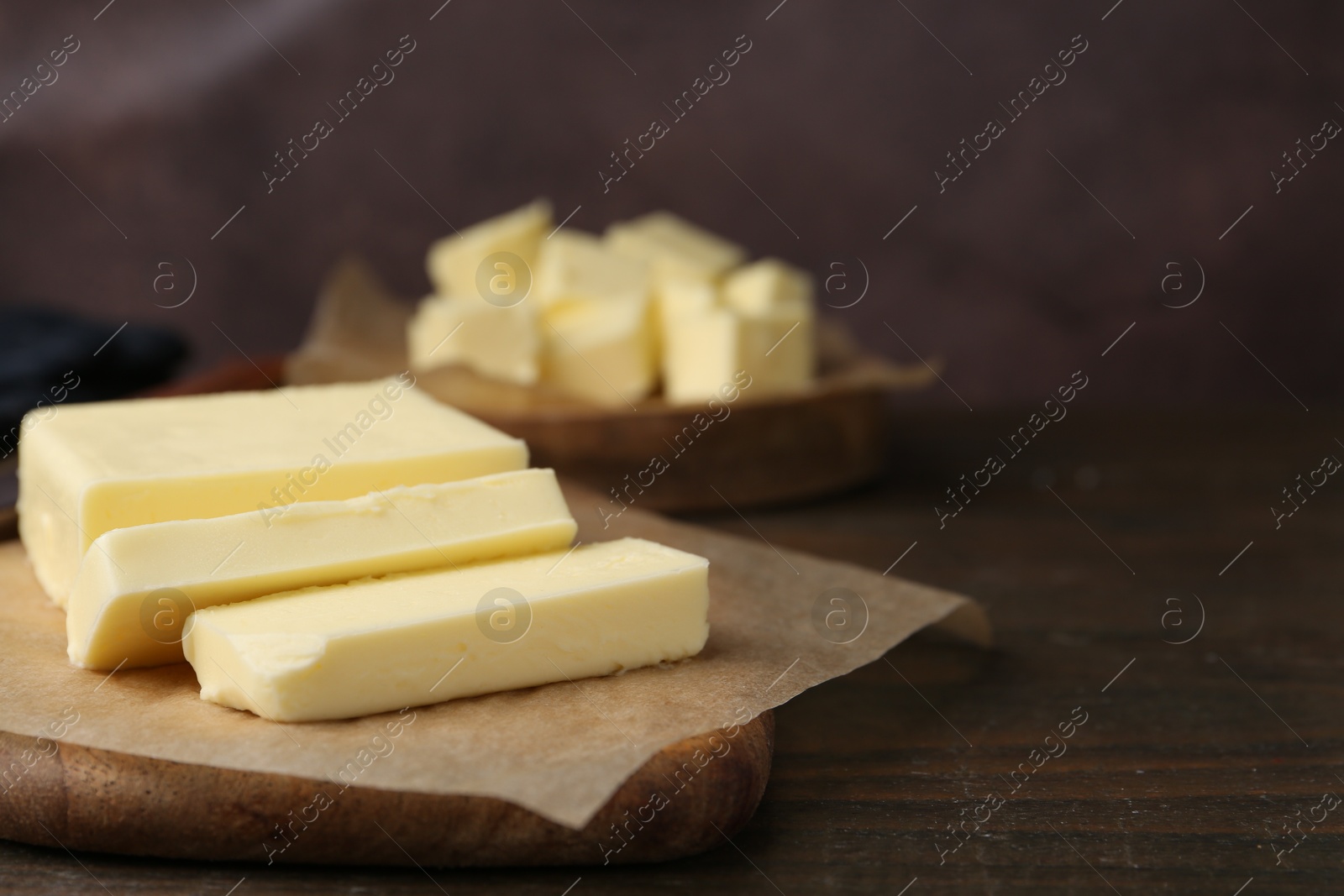 Photo of Pieces of fresh butter on wooden table, closeup. Space for text