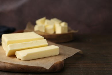 Photo of Pieces of fresh butter on wooden table, closeup. Space for text