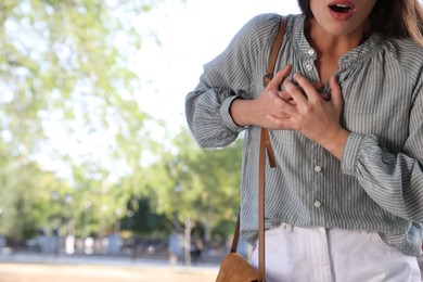 Young woman having heart attack in park, closeup