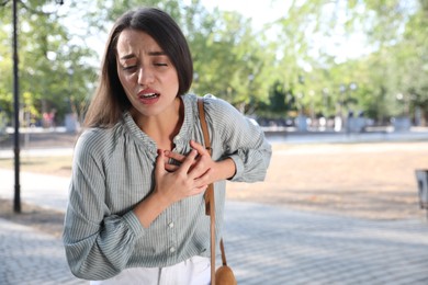 Young woman having heart attack in park