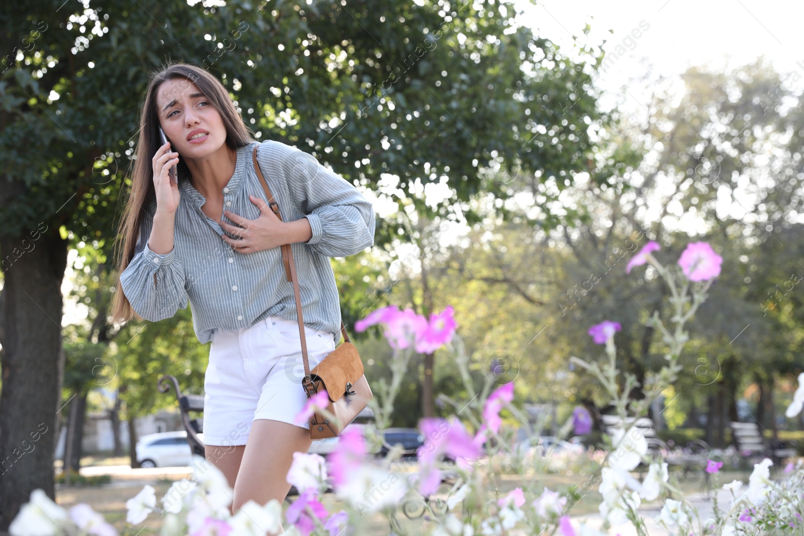 Photo of Young woman with heart attack calling ambulance in park