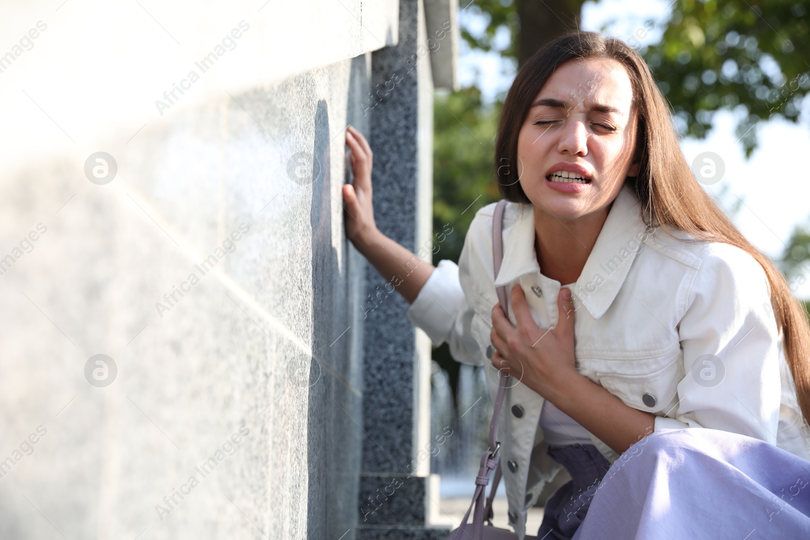 Photo of Young woman having heart attack on city street